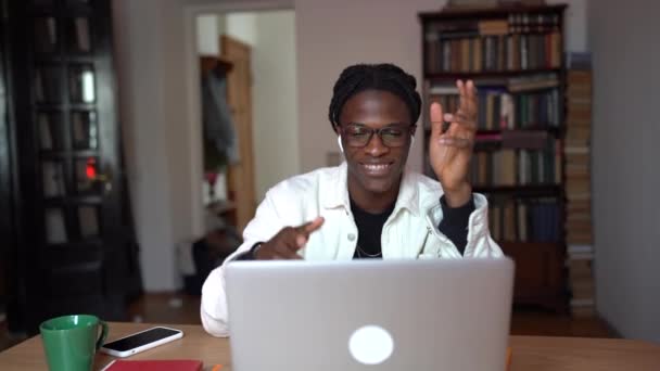 楽観的なアフリカ系アメリカ人の男性が手を振って笑顔大学の友人とビデオ通話をしている インターネット放送中に加入者とチャットノートパソコンを見て幸せな正の黒の学生 — ストック動画