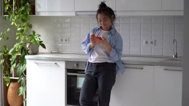 Счастливая Улыбающаяся Азиатка Стоящая Кухне Держа Смартфон Получает Приятное Романтическое — стоковое видео