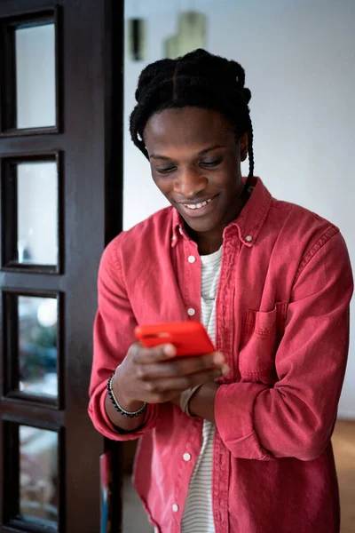 Young happy African American guy holding smartphone feeling excited receiving good positive news. Smiling black man getting romantic text message from girlfriend, chatting through online dating app