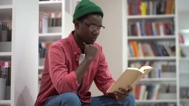 Smart Fokuserad Afroamerikansk Manlig Student Som Noggrant Studerar Bokens Vändsidor — Stockvideo