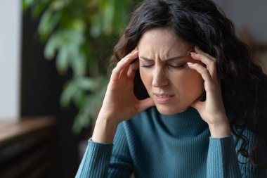 Stressed worried young woman suffering from headache, frustrated female with closed eyes massaging temples for migraine relief, worrying about family problems, selective focus. Anxiety disorder