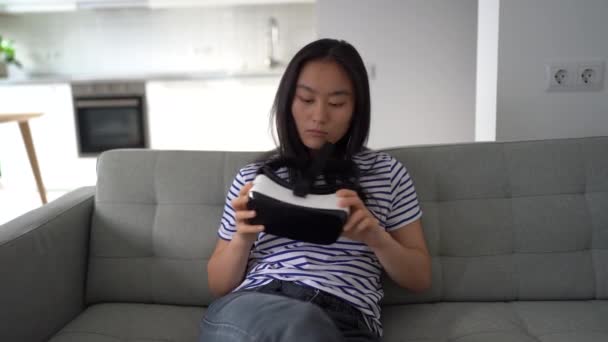 Confused Pensive Asian Woman Twists Hands Examines Glasses Sits Couch — Vídeo de Stock