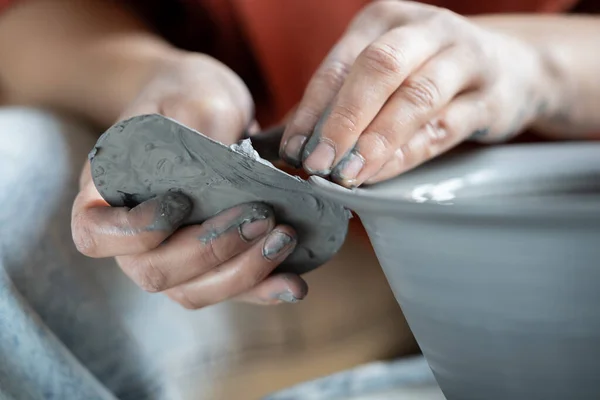 stock image Close up of female hands shaping clay with sculpting tool using trimming knife, ceramist holding metal rib while making pottery on wheel, potter using steel scraper in work. Handmade stoneware concept