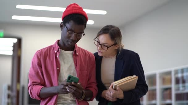 Двоє Багаторасових Студентів Африканський Хлопець Кавказька Дівчинка Дивляться Відео Смартфон — стокове відео