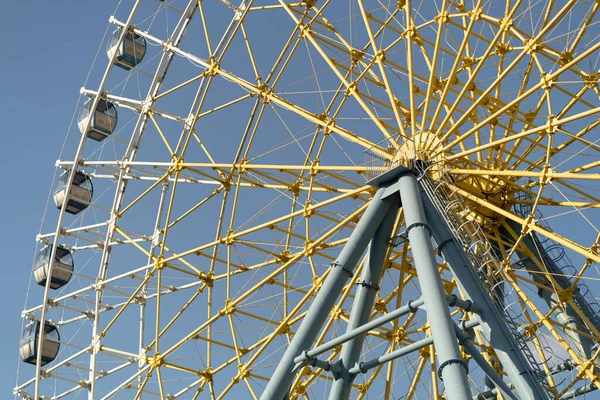 Giant observation wheel with passenger cabs against blue sky at Mtatsminda Park in Tbilisi, Georgia. Popular amusement ride giving visitors breathtaking view of city
