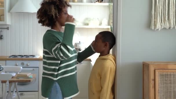 Smiling Loving African American Mother Measuring Height Child Son Home — Wideo stockowe