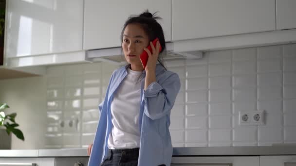 Молодая Удивила Азиатку Разговаривающую Телефону Стоя Дома Кухне Взволнованная Женщина — стоковое видео