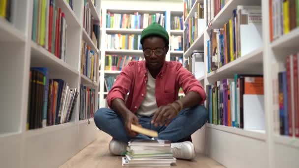 African American Student Guy Wearing Glasses Sitting Cross Legged Bookcases — Video Stock