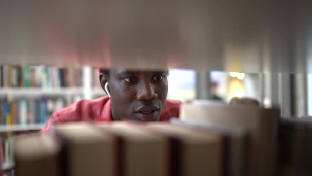 Афроамериканський Студент Стоїть Між Книжковими Полицями Бібліотеці Шукаючи Наукову Літературу — стокове відео