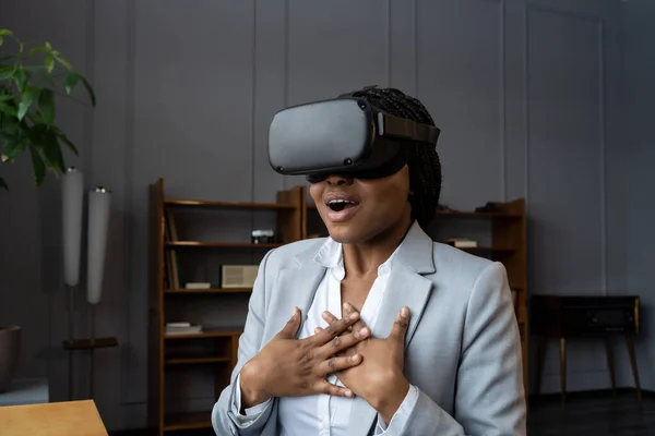 在Vr耳机中的情绪震惊的非洲女性员工沉浸在充满情感和印象的3D虚拟世界中 在第一次虚拟现实体验中坐在工作场所 尖叫着哇 — 图库照片