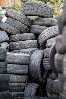 Old used rubber tires stacked with high piles. Tyre dump. Hazardous waste requiring recycling and disposal. 