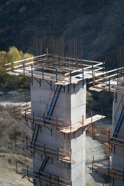 支持正在建造的带有木制脚手架和建筑商梯子的桥梁 难以到达山区的铁路或公路交通运输基础设施建设进程 — 图库照片