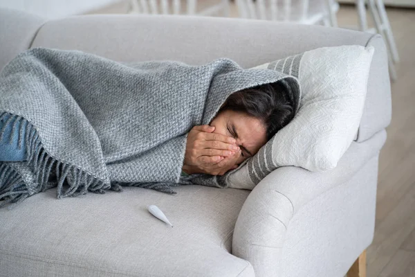 Unhappy Sickly Woman Sneezes Covering Face Hands Lies Sofa Wrapped — Stock fotografie