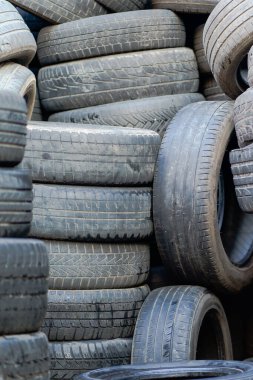 Old used rubber tires stacked with high piles. Tyre dump. Hazardous waste requiring recycling and disposal. 