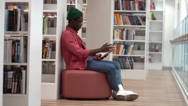 Jovem Tipo Africano Milenar Lendo Livro Livraria Sentado Otomano Deitado — Vídeo de Stock