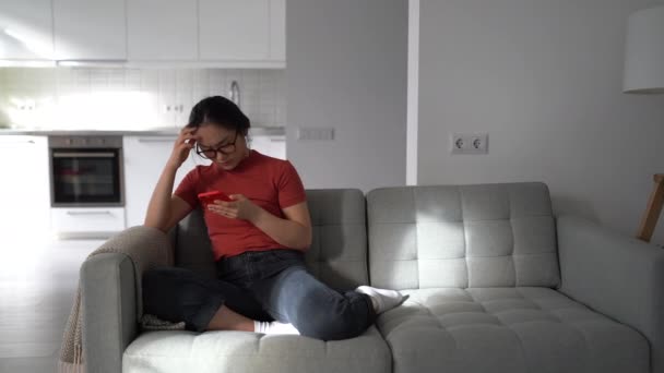 Nervous Anxious Asian Woman Phone Sits Couch Throws Glasses Angrily — Vídeo de Stock