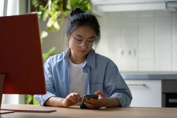 Young Asian Female Freelancer Scrolling Her Phone While Sitting Desk — Fotografia de Stock