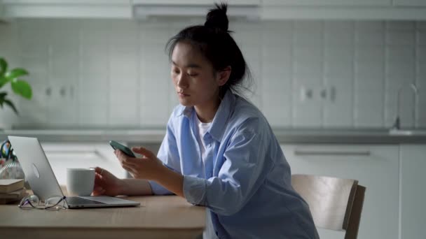 Girişimsiz Asyalı Kadının Telefonda Sosyal Medyaya Göz Atması Mutfak Masasında — Stok video