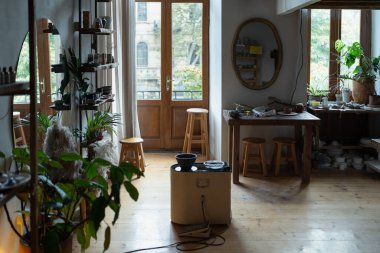 Interior of ceramist workshop or hall for teaching lessons on making pottery with potter wheel on pedal set. Shop for manufacture and sale of porcelain dishes and modeling courses from natural clay