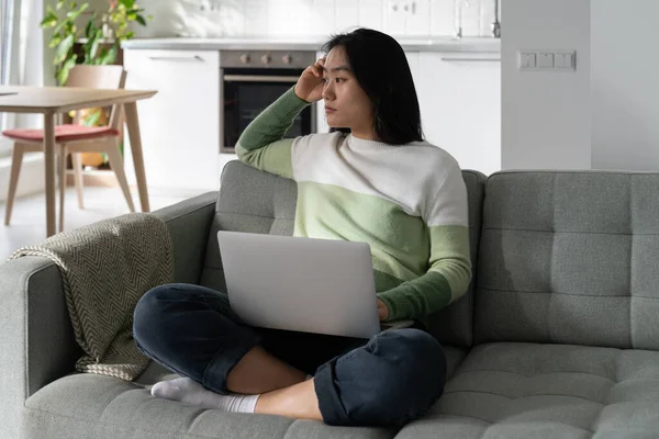 Thoughtful Asian Woman Freelancer Tired Sits Sofa Laptop Lap Suffering — Stockfoto