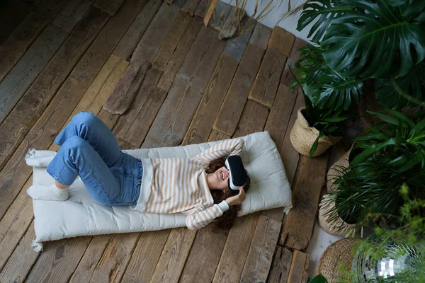 stock image Excited young woman watch funny video wearing vr glasses laugh using virtual reality interface, top angle view. Overjoyed hilarious female enjoy digital simulation goggles device for leisure activity