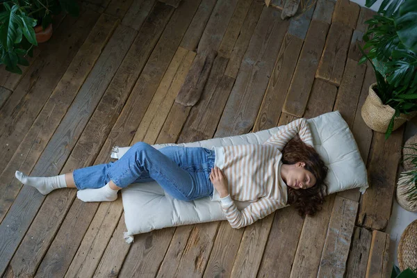 松懈的意大利女人躺在家里的木地板上 下班后休息 俯瞰平静的年轻西班牙女性睡在被热带室内植物环绕的床垫上 健康概念 — 图库照片