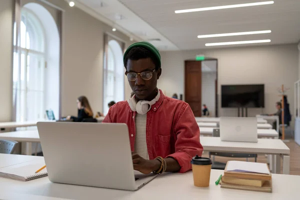 认真的美国黑人学生完成了虚拟教育的听力训练 摘下耳机开始在大学或学院图书馆的课堂上通过学习材料的测试 — 图库照片