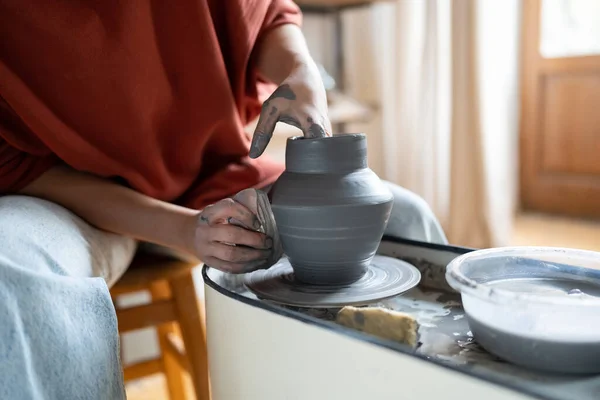 Craftswoman enjoying meditative process of making ceramics, female ceramist shaping clay on pottery wheel while working in studio, selective focus. Craft business and creative hobby concept
