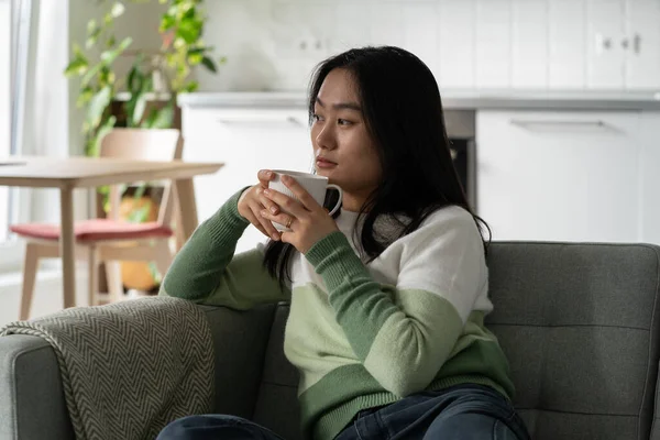 Entspannt Sitzt Die Nachdenkliche Asiatin Lässiger Kleidung Auf Dem Sofa — Stockfoto