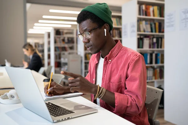 集中型のアフリカ系アメリカ人の学生は ノートパソコン画面の接続を見て 講義教材を議論するか ビデオ通話を使用して教師と外国語を勉強します — ストック写真