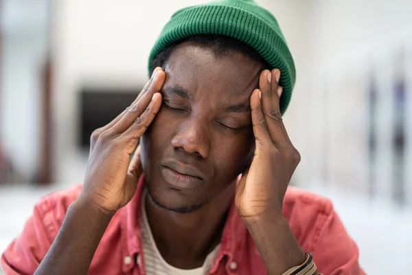 問題に悩まされる疲れアフリカ系アメリカ人の男性のフリーランスは 手で閉じた目のタッチヘッドで座っていると不安を感じています 期限切れについて頭痛の種と疲れ過ぎた黒人男は考える — ストック写真
