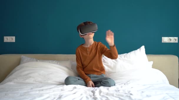 仮想世界でVrメガネをかけている興味のある子供はゴーグルモバイルアプリを使っています 教育やシミュレーションゲームメニュー項目の選択のためのデジタル3Dインターフェイスと相互作用学校の少年 — ストック動画