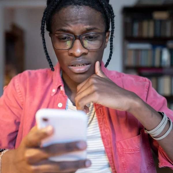 爱社交的全神贯注的非裔美国男人拿着手机 通过短信与女友聊天 年轻的黑人用智能手机与朋友交流 并在社交网络上调情 — 图库照片