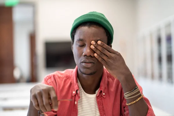 燃え尽きてるぞ 何千人ものアフリカの男学生が頭痛や片頭痛に苦しんで目をマッサージし 図書館で長時間勉強しながらやる気を失い 選択的な焦点 — ストック写真