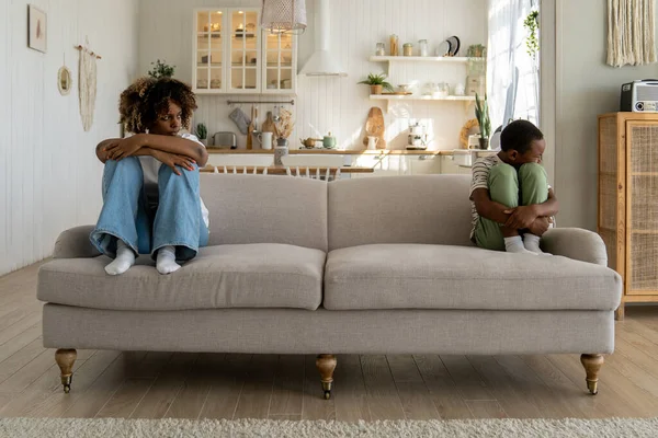 アフリカ系アメリカ人の母親と子供の少年は 自宅で口論した後 沈黙を無視して配置ソファの反対側に座っている 心配な女は動揺した息子に不満を持っている — ストック写真