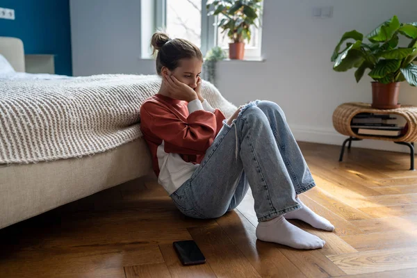 우울증에 소녀는 친구의 전화가 오기를 기다리며 바닥에 기뻐하지 않으며 메시지를 — 스톡 사진