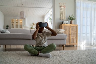 Öğrenmek için sanal gerçeklik teknolojisini kullanan öğrenci çocuk. Çocuklar için artırılmış gerçeklik. Afro-Amerikalı çocuk oturma odasında oturmuş sanal gerçeklik kulaklığı takıyor ve sanal dünyayı keşfediyor.. 