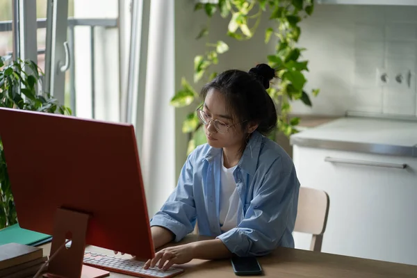 焦点を当てたアジアの女性It開発者は 自宅からリモートで作業しながら眼鏡書き込みコードを身に着けています 自宅からリモートで作業しながら デスクトップコンピュータコーディングプログラミングを見てキーボードを入力します — ストック写真