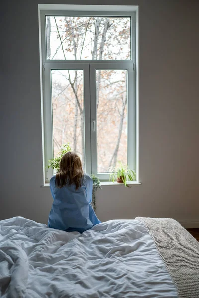 stock image Rear view of lonely woman sitting on bed at home, sad single female feeling depressed, thinking of life purpose, coping with loneliness after break up. Women and depression concept