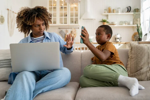 Zdenerwowany Niezależny Rodzic Afroamerykanka Matka Siedzi Kanapie Laptopem Prosząc Dziecko — Zdjęcie stockowe