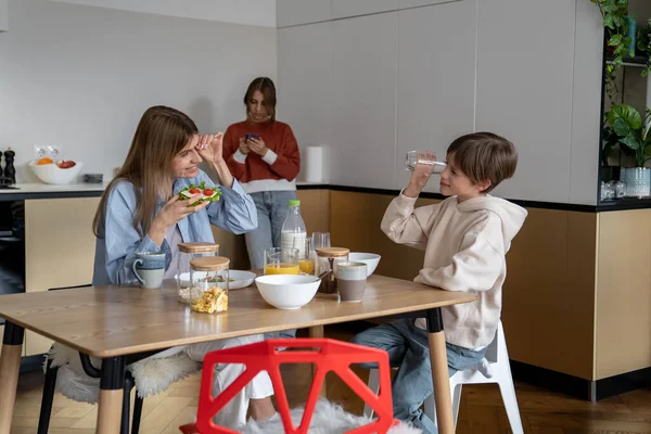 Happy Mother Son Eating Together Morning Teen Girl Using Smartphone — Stock Photo, Image