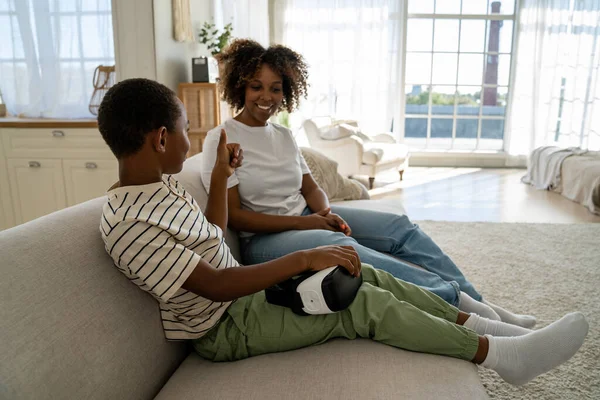 stock image Joyful African American little boy making thumb up gesture for mother after play video game virtual reality headset. Pleased mom interested in opinion of son about VR 3D glasses for smartphone at home