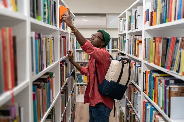 Американский Студент Ботаник Выбирает Книгу Университетской Библиотеке Беря Книжной Полки — стоковое фото