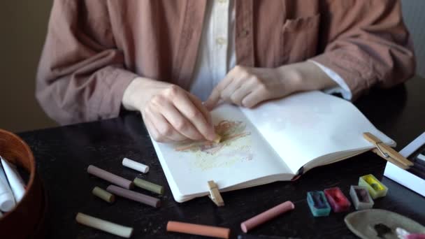 テーブルに座るパステルチョークを使用してアルバムの自然家の中で女性画家の絵を描く 手をクローズアップ 女子美術生は宿題をする絵画の技術を練習する 絵画教室のコンセプト — ストック動画