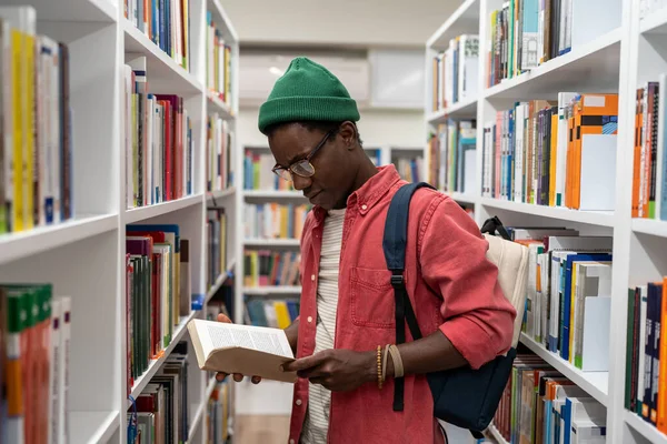 热情洋溢的非洲裔美国学生在大学图书馆里选择研究教科书 男子嬉皮士在公共场所看书 接受教育 传授知识概念 — 图库照片