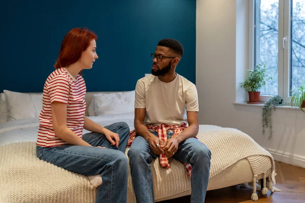 年轻的跨种族夫妇夫妻坐在床上讨论亲密问题 有分歧和误解 谈论关系问题 婚姻危机 — 图库照片