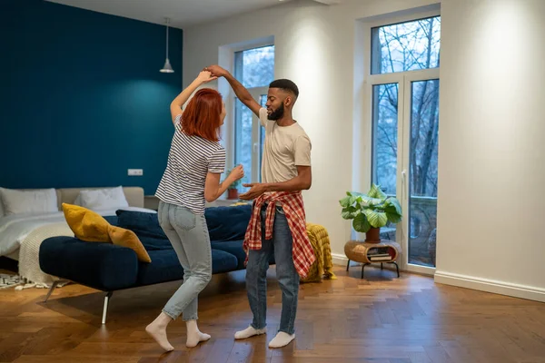 ロマンチックな異人種間の若い家族のカップルの妻と夫が一緒に音楽に合わせて踊り 笑顔で一緒に楽しみ 週末にパートナーと家で無料の時間を過ごす 幸せな関係 — ストック写真