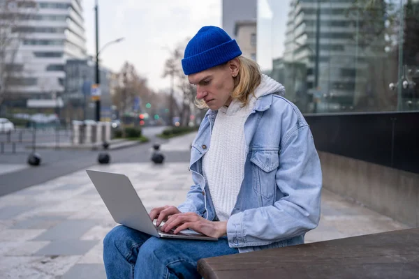 认真专注的千年嬉皮士男自由职业者坐在城市街道上用笔记本电脑键盘打字 男性企业家被紧急邮件淹没 工作休息时在网上工作 — 图库照片