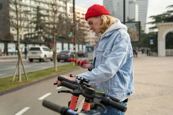 Hipster Cara Desbloquear Scooter Com Telefone Celular Rua Cidade Perto — Fotografia de Stock