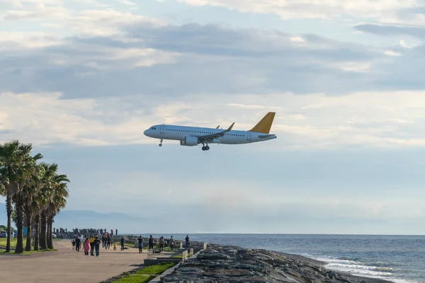 stock image Airplane landing at sunrise over Black Sea in Batumi Georgia. People watching plane landing standing on the sea embankment. Trip, avia travel concept. 